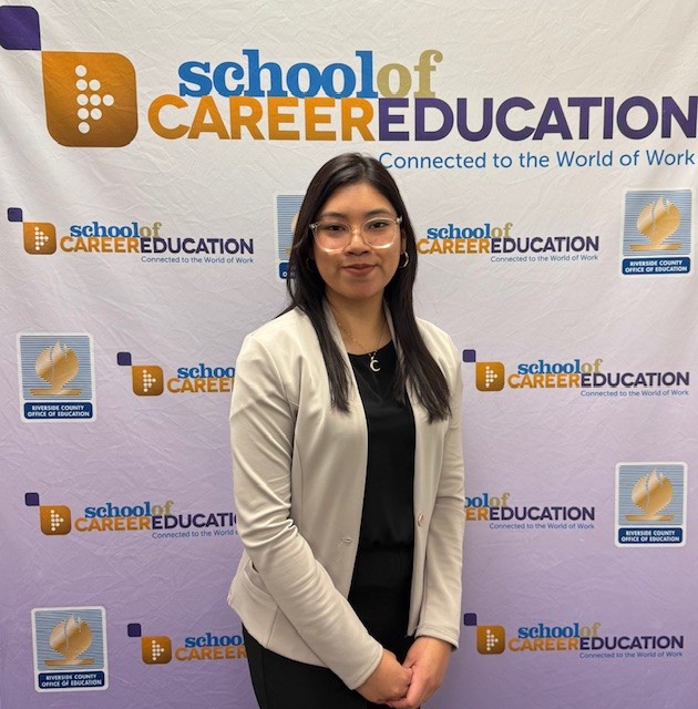 Instructor in front of School of Career Education banner