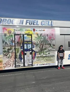 Antonio standing in front of his artwork displayed on a bus 