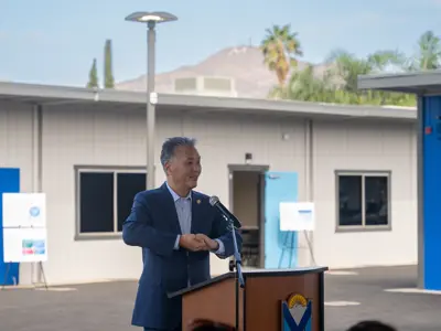 Speaker holding both hands together in gesture of collaboration