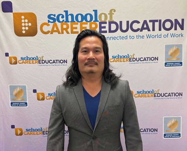 Instructor in front of School of Career Education banner