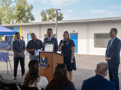 Woman speaking with dignitaries standing with her at the podium