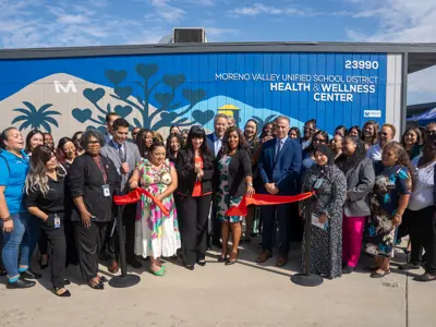 Ribbon falling after ceremonial cutting in front of Moreno Valley Unified School District Wellness Center mural