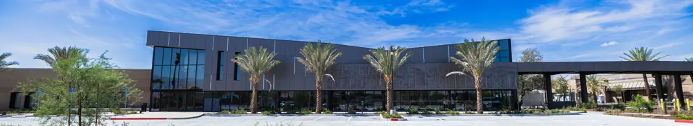 Riverside County Office of Education single story modern brick conference center building lined with palm trees.