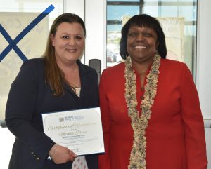 Woman poses with Certificate of Recognition next to dignitary