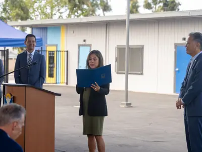 Woman holding microphone and reading from a portfolio