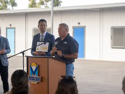 Man speaking with dignitary at his side