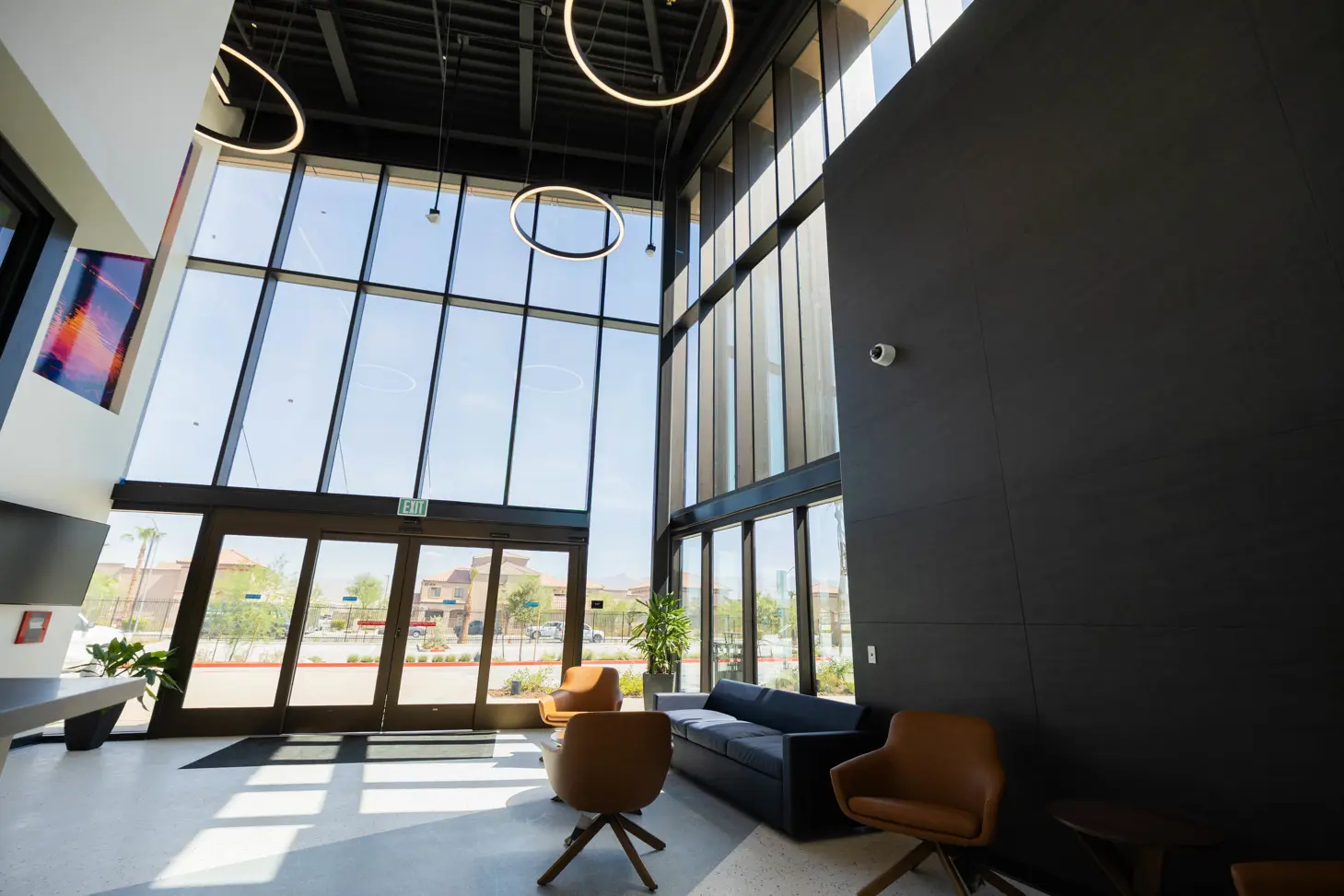 Comfortable lobby area with high open ceiling construction, looking out into parking lot.