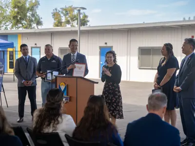 Young woman applauding holding microphone with dignitaries standing in support