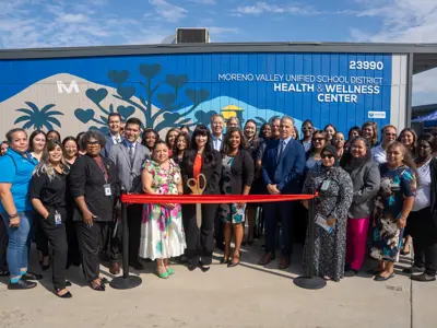 Group ready for ribbon cutting in from of the Moreno Valley Unified School District Wellness Center mural